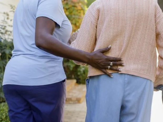 A caregiver steadying a senior while walking outdoors